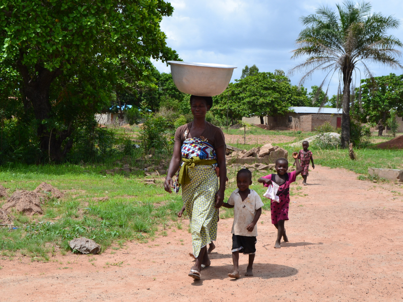 Woman with bucket of water on head walking with children