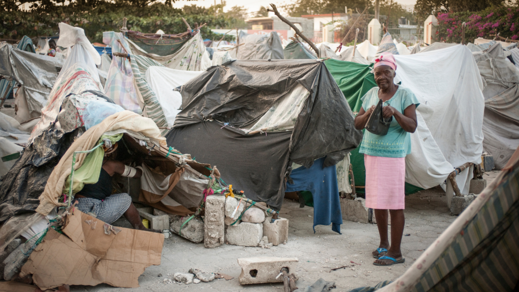 Haitian lady standing next to makeshift tents